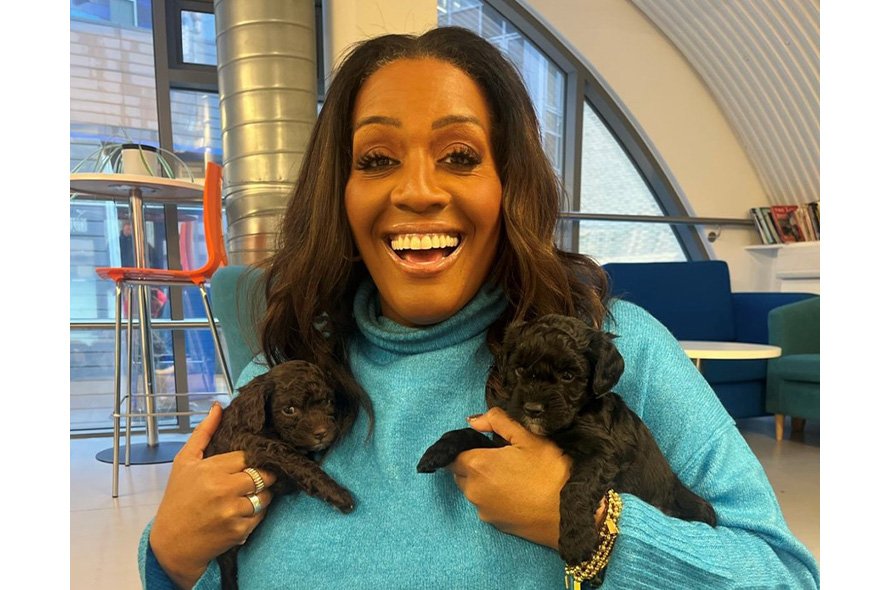 Alison Hammond holding two black puppies