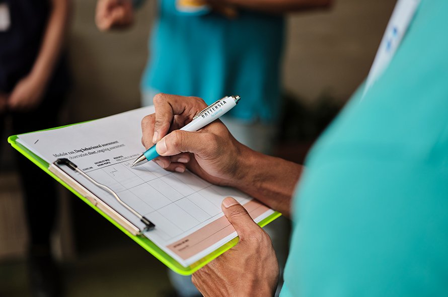 Person writing on a piece of paper attached to a clipboard