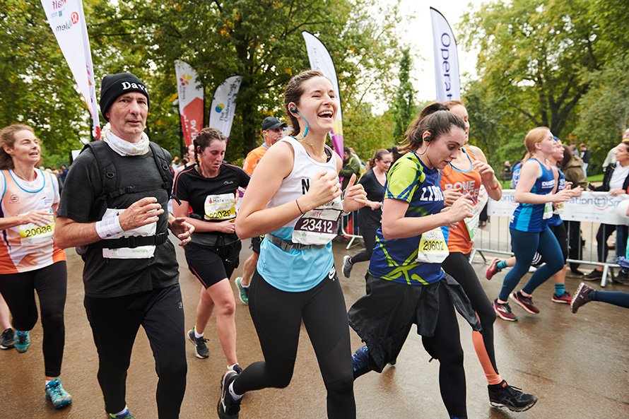 Woman wearing a Battersea running top running and smiling as they take part in running fundraising event