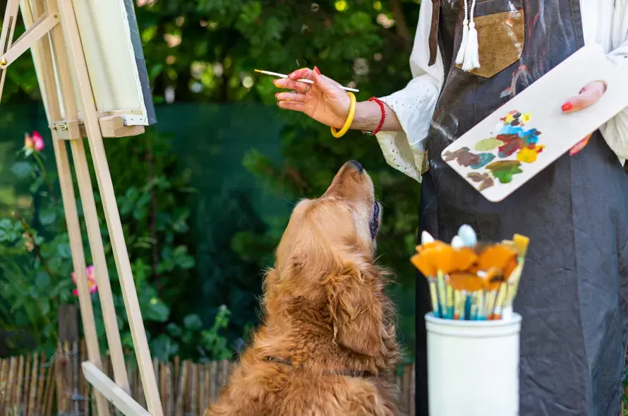 A dog looking up at a person painting