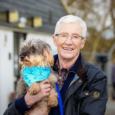 Paul O'Grady holding his Battersea dog Sausage